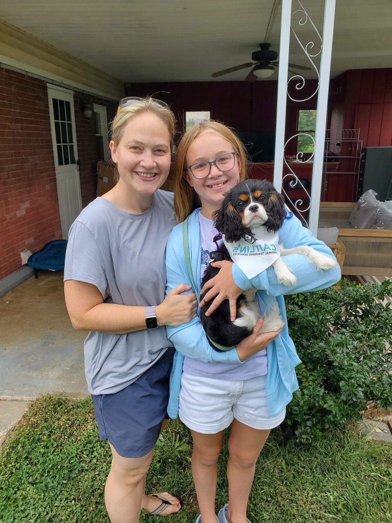 Mother and daughter holding their puppy after completing training